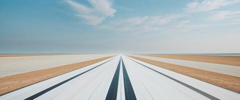 An empty runway with a blue sky in the background photo