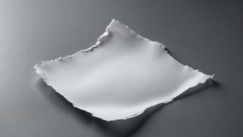 A piece of torn white paper displays rugged edges on a smooth surface with gentle lighting. photo