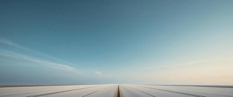 Long empty runway stretching into the horizon under a clear blue sky. photo