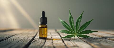 Cbd oil and cannabis leaf on wooden table photo