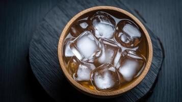 Ice cubes in a wooden bowl on a black background photo
