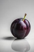 Close-up of Ripe Plum with Stem and Reflection on White Surface photo