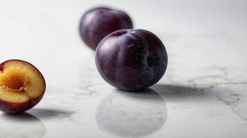 Plum Still Life Featuring Whole and Halved Fruit on Marble Surface photo