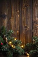 Festive Green Pine Branch and Warm String Lights Against Rustic Wood Backdrop photo