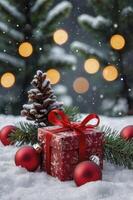 Christmas Gift with Red Ribbon and Ornaments in Snowy Winter Scene photo