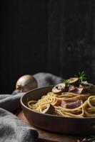 Serving Spaghetti Carbonara with Mushroom and Ham in Moody Lighting photo