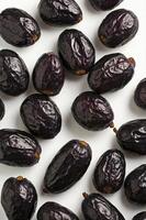 Close Up Arrangement of Fresh Black Dates on White Background photo