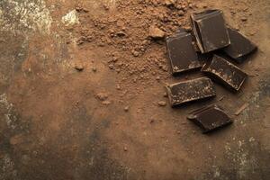 Dark Chocolate Chunks with Cocoa Powder on Rustic Background Overhead View photo