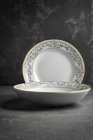 Elegant Porcelain Plates Stacked with Gold Trim on Dark Textured Background photo