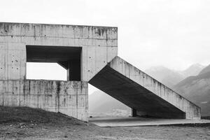 Monochrome Image of Concrete Building Against Mountain Backdrop on Cloudy Day photo