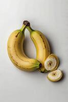 Ripe Yellow Bananas and Slices on White Surface Still Life photo