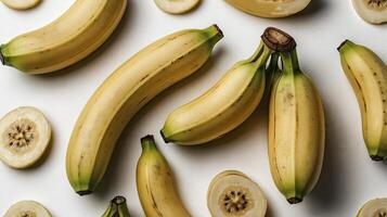 Arrangement of Fresh Yellow Bananas and Slices on a White Surface photo