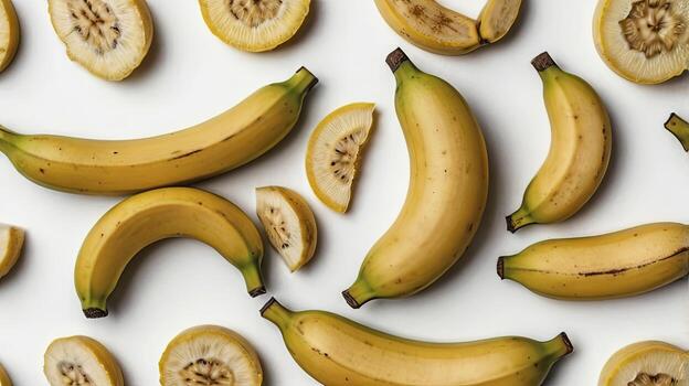 Fresh Whole and Sliced Bananas on a White Surface Overhead View photo
