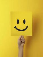 Holding Yellow Smiley Face Sign Against a Vibrant Background with One Hand photo