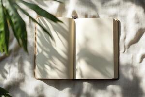 Open Blank Notebook on Linen Surface with Plant Shadow Overlay photo
