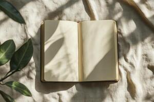 Open Blank Notebook with Leaf Shadows on Fabric Background Flat Lay photo