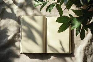 Open Notebook on Linen with Leaves and Sunlight for Writing Ideas photo