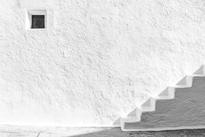 White Wall with Small Window and Steps Leading Upward in Sunlight photo