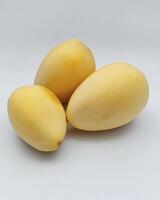 Three Yellow Dates Fruit Arranged on a White Surface Close Up photo