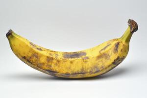 Ripe Yellow Banana with Brown Spots on a Plain Background photo