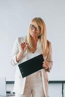 Woman in formal clothes standing with notepad and teaching business in the class photo
