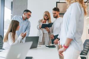 With notepad. Analyzing data. Group of professional business people is in the office photo