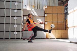 Kicking a soccer ball on the break time. Storage worker is in the warehouse with bunch of products photo