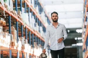 Portrait of storage worker that is in the warehouse with bunch of products photo