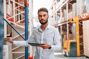 Portrait of storage worker that is in the warehouse with bunch of products, photo