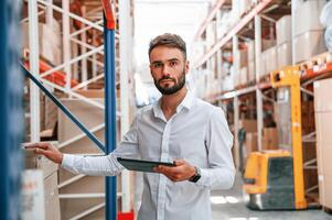 Portrait of storage worker that is in the warehouse with bunch of products. photo