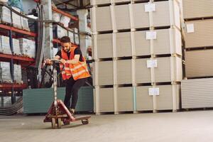 Riding, the platform trolley.. Storage worker is in the warehouse with bunch of products photo