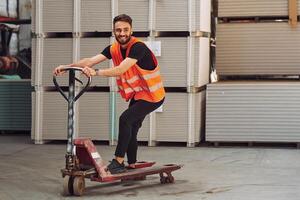 Riding ,the platform trolley. Storage worker is in the warehouse with bunch of products photo