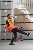 Playing soccer.. Storage worker is in the warehouse with bunch of products photo