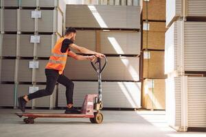 Riding, the platform trolley. Storage worker is in the warehouse with bunch of products photo