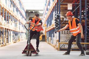 Man riding trolley platform,. Having fun. Two storage workers is in the warehouse photo