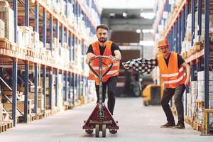Man riding trolley platform. ,.Having fun. Two storage workers is in the warehouse photo