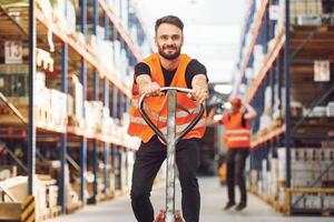 Having fun by using trolley platform. Two storage workers is in the warehouse photo