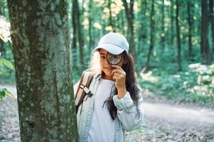 Using magnifying glass., Girl is in the forest at summer day time discovering new places photo