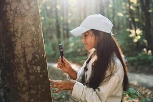 With magnifying glass. Girl, is in the forest at summer day time discovering new places photo