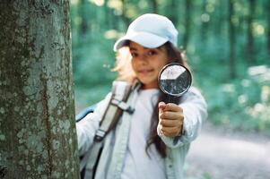 Using magnifying glass. ,Girl is in the forest at summer day time discovering new places photo