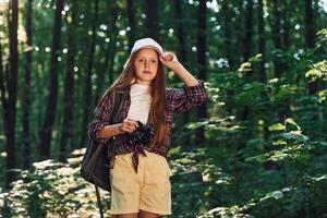 Young photographer with camera.. Girl is in the forest at summer day time discovering new places photo