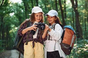 Standing, on the footpath. Two girls is in the forest having a leisure activity, discovering new places photo
