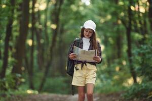 Using the map.. Girl is in the forest at summer day, time discovering new places photo