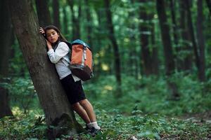 Leaning on the tree... Girl is in the forest at summer day time discovering new places photo