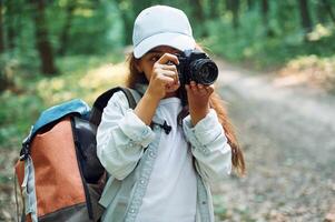 Using professional camera.. Girl is in the forest at summer day time discovering new places photo