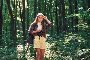 Young, photographer ,with camera. Girl is in the forest at summer day time discovering new places photo