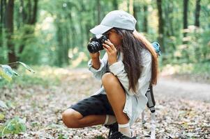 Using professional camera., Girl is in the forest at summer day time discovering new places photo