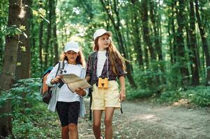Using ,the map. Two girls is in the forest having a leisure activity, discovering new places photo