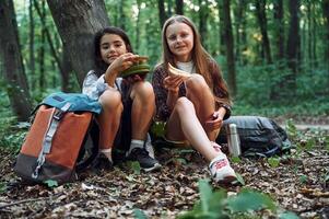 Sitting and eating. Two girls is in the forest having a leisure activity, discovering new places photo