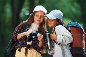 Front view of two girls that is in the forest having a leisure activity photo